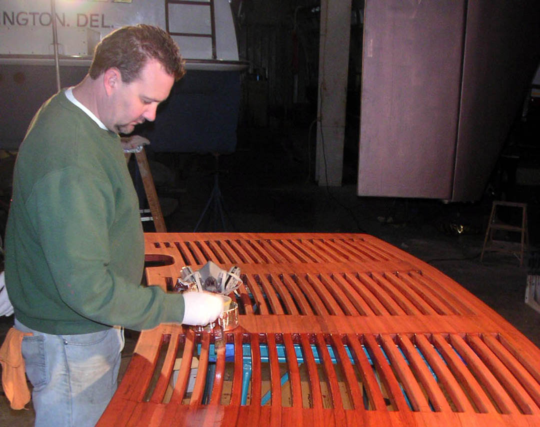 Marine technician varnishing a wooden hull